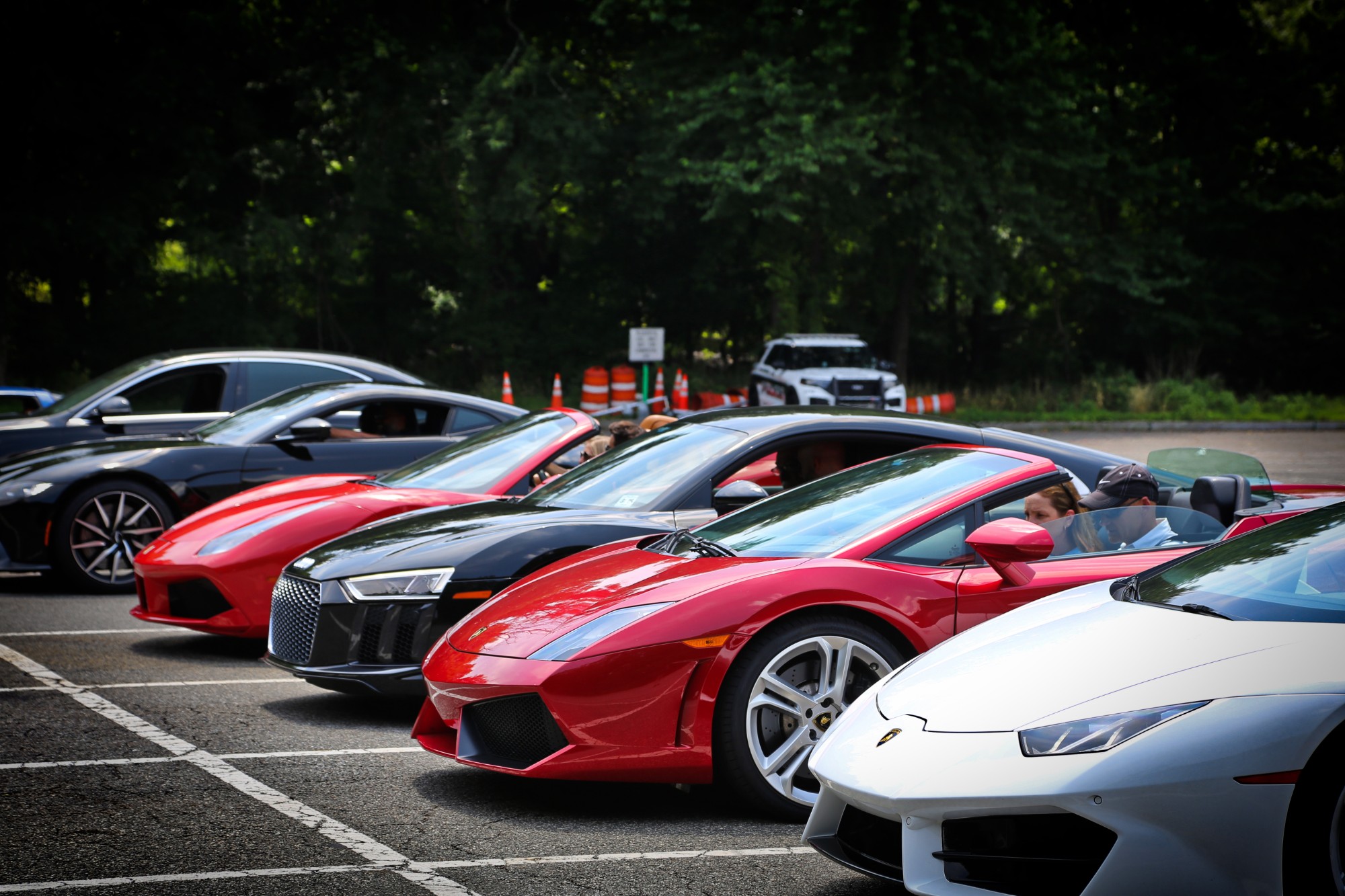Tour cars lined up nose to tail at the start — white Lamborghini Huracán, red Gallardo, black Audi R8 and a red Ferrari 488 with drivers in their seats