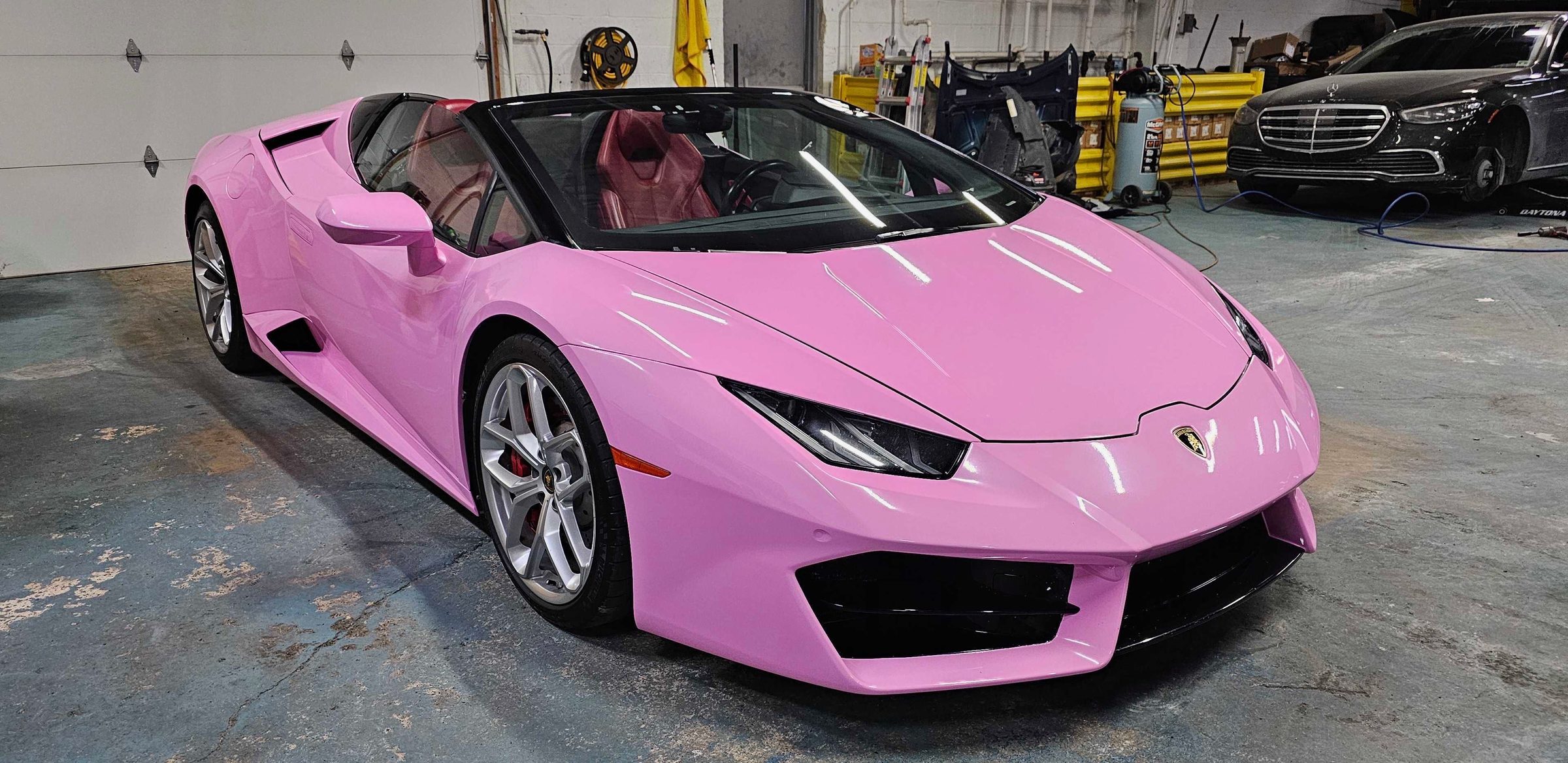 A pink Lamborghini Huracán Spyder with the roof down in our garage